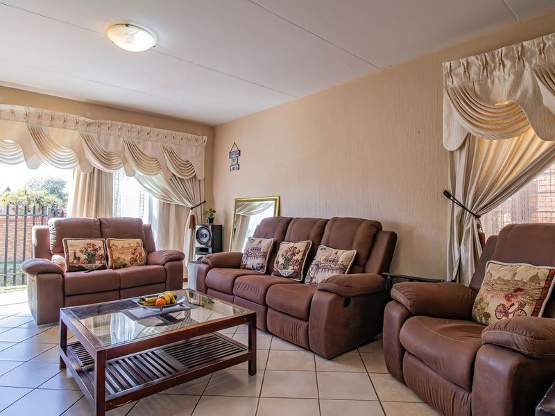 A spacious living room featuring tiled flooring and a large sliding glass door providing access to the exterior.