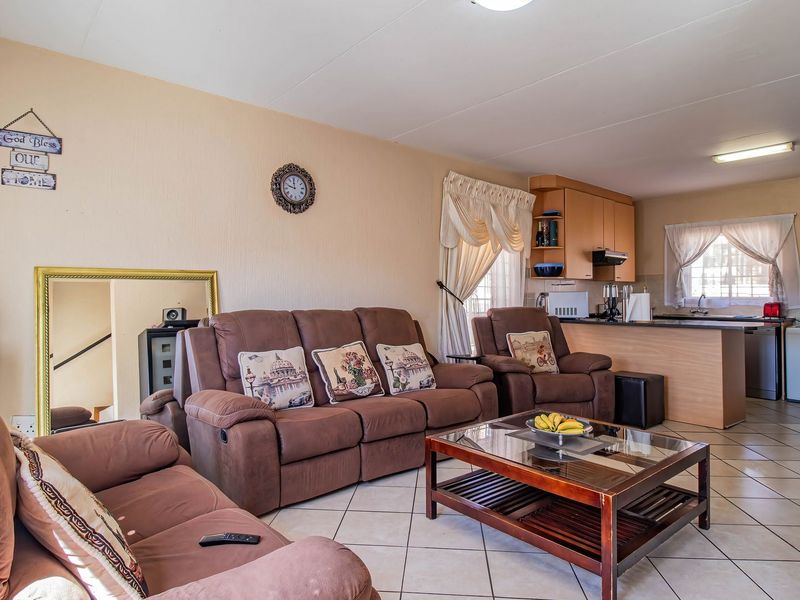 Open-plan living area featuring tiled flooring and a functional kitchen with built-in cabinetry and a breakfast bar, creating a cohesive living space.