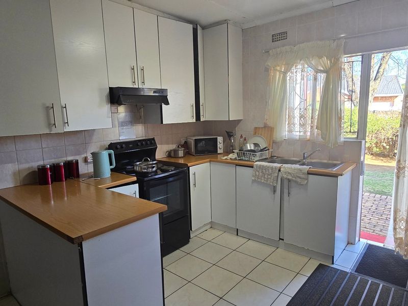 Functional kitchen featuring white cabinetry, laminate countertops, tiled backsplash, and direct access to the outdoor area through a sliding glass door.