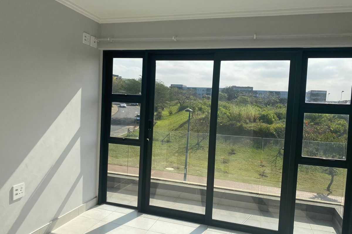 A bright, empty living area featuring large sliding glass doors that provide ample natural light and views of the surrounding landscape.