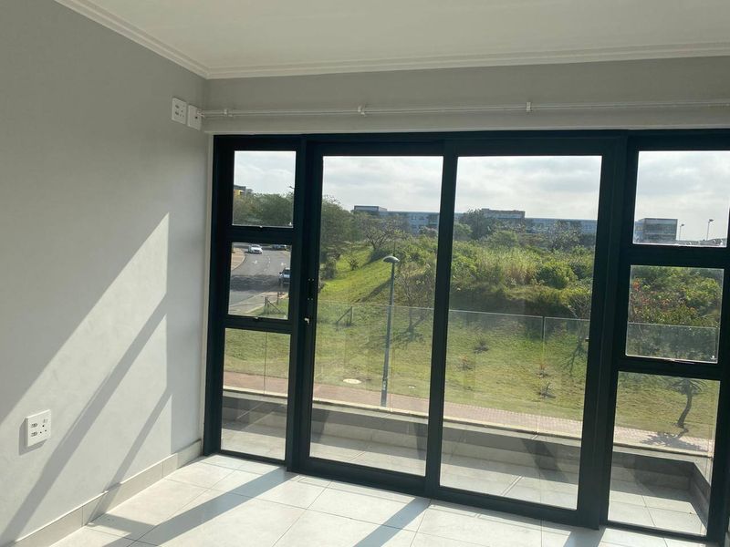 A bright, empty living area featuring large sliding glass doors that provide ample natural light and views of the surrounding landscape.