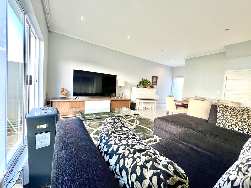 Spacious open-plan living and dining area featuring tiled flooring, recessed downlighting, and large sliding glass doors providing ample natural light.