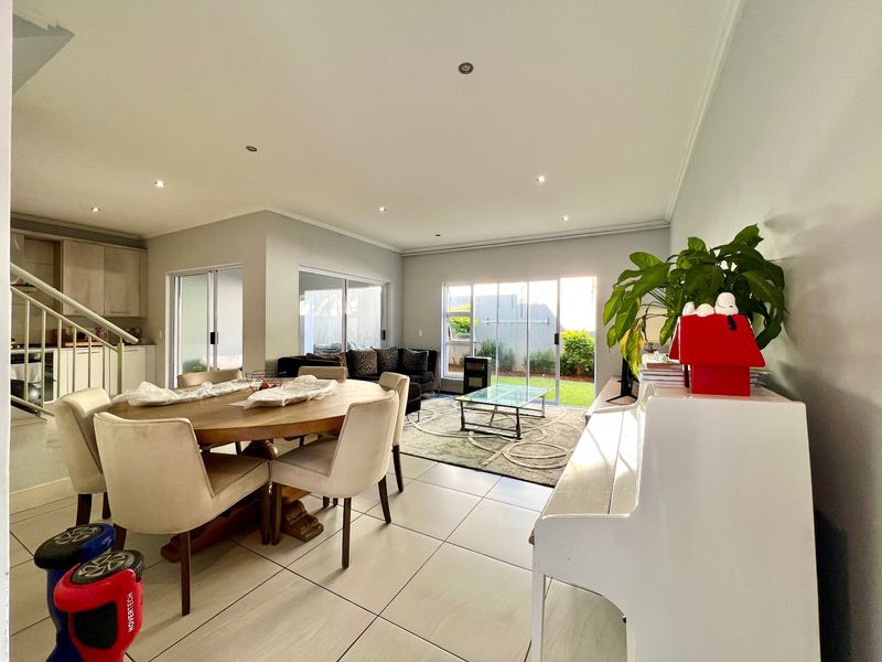 Spacious open-plan living and dining area featuring large sliding glass doors, neutral tiled flooring, recessed lighting, and direct access to the rear garden.