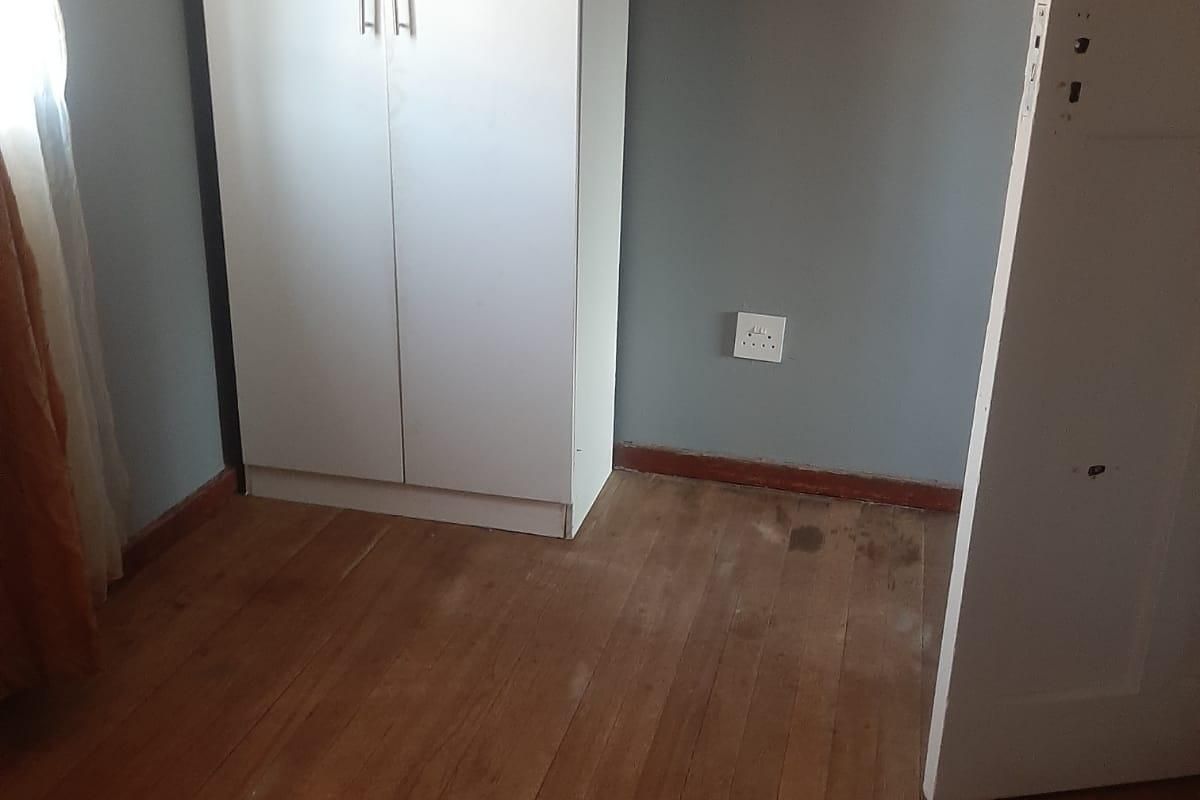 A vacant bedroom featuring original timber flooring and neutral wall paint, offering a blank canvas for potential renovation or interior design updates.