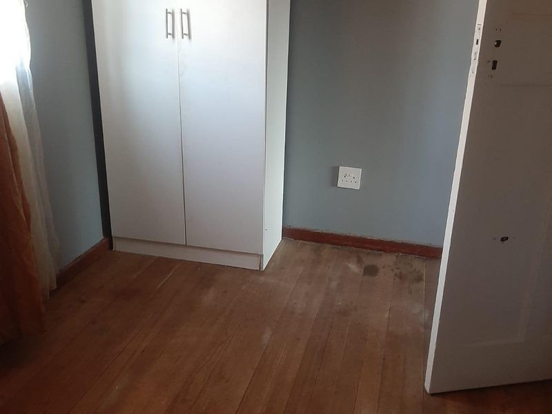 A vacant bedroom featuring original timber flooring and neutral wall paint, offering a blank canvas for potential renovation or interior design updates.