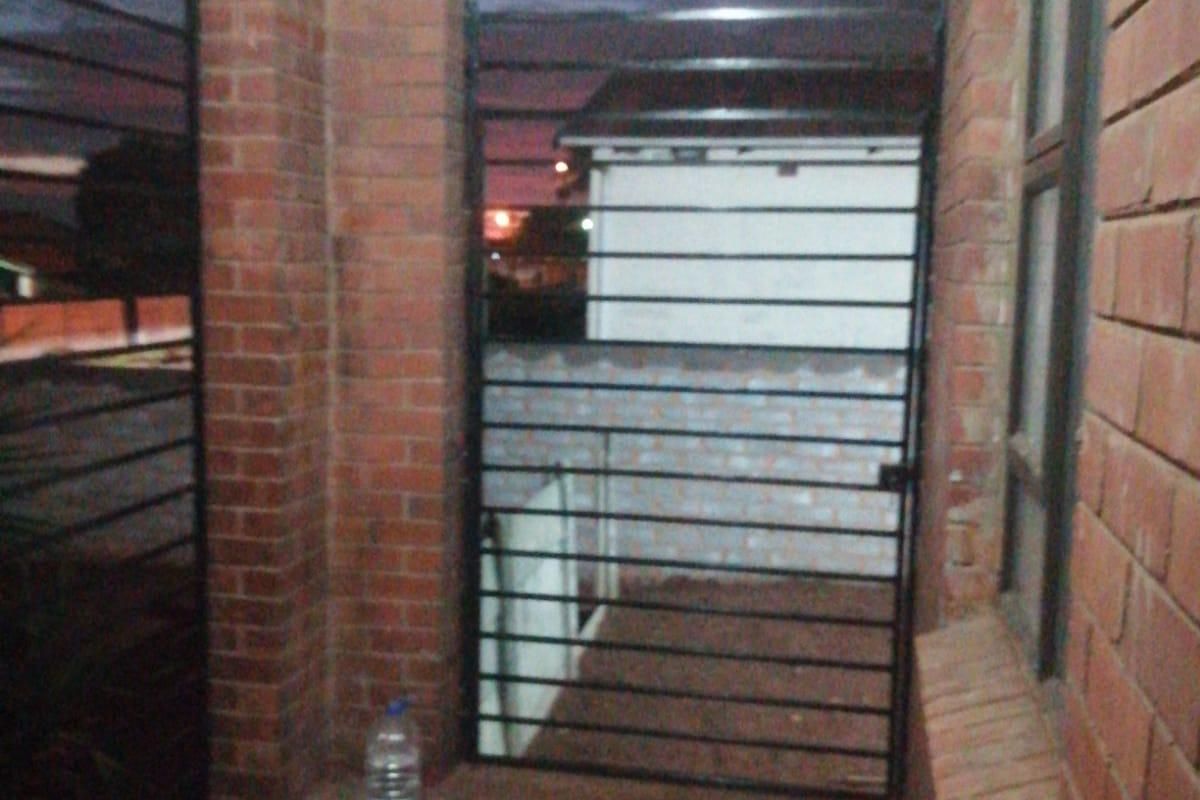 A covered patio area featuring brick pillars and security gates, providing a secure outdoor transition space.