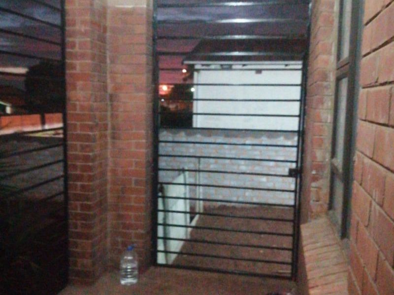 A covered patio area featuring brick pillars and security gates, providing a secure outdoor transition space.