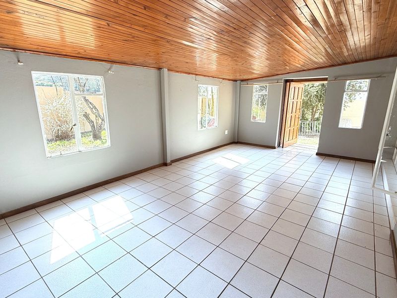 Spacious, empty living area featuring a warm timber tongue and groove ceiling, neutral tiled flooring, and direct access to the exterior.