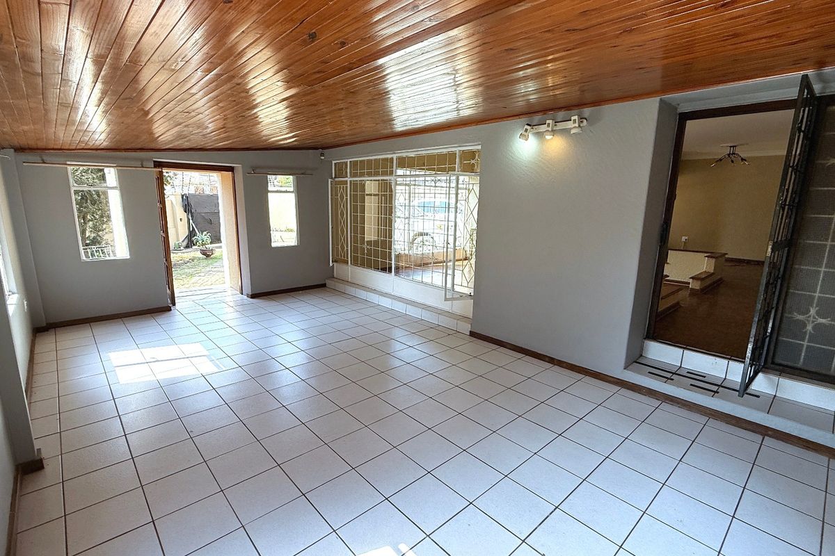 Spacious living area featuring a timber tongue and groove ceiling, ceramic tiled flooring, and direct access to the exterior through security-fitted doors.