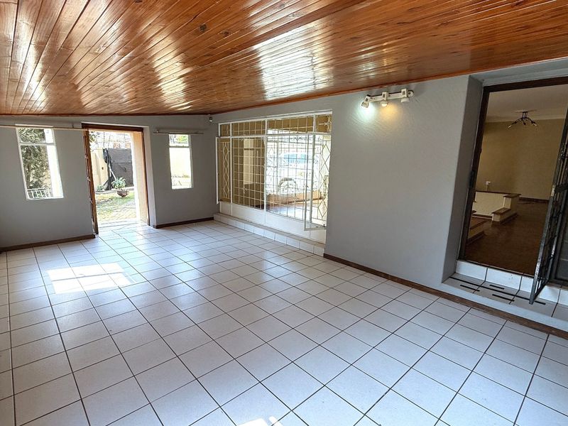 Spacious living area featuring a timber tongue and groove ceiling, ceramic tiled flooring, and direct access to the exterior through security-fitted doors.