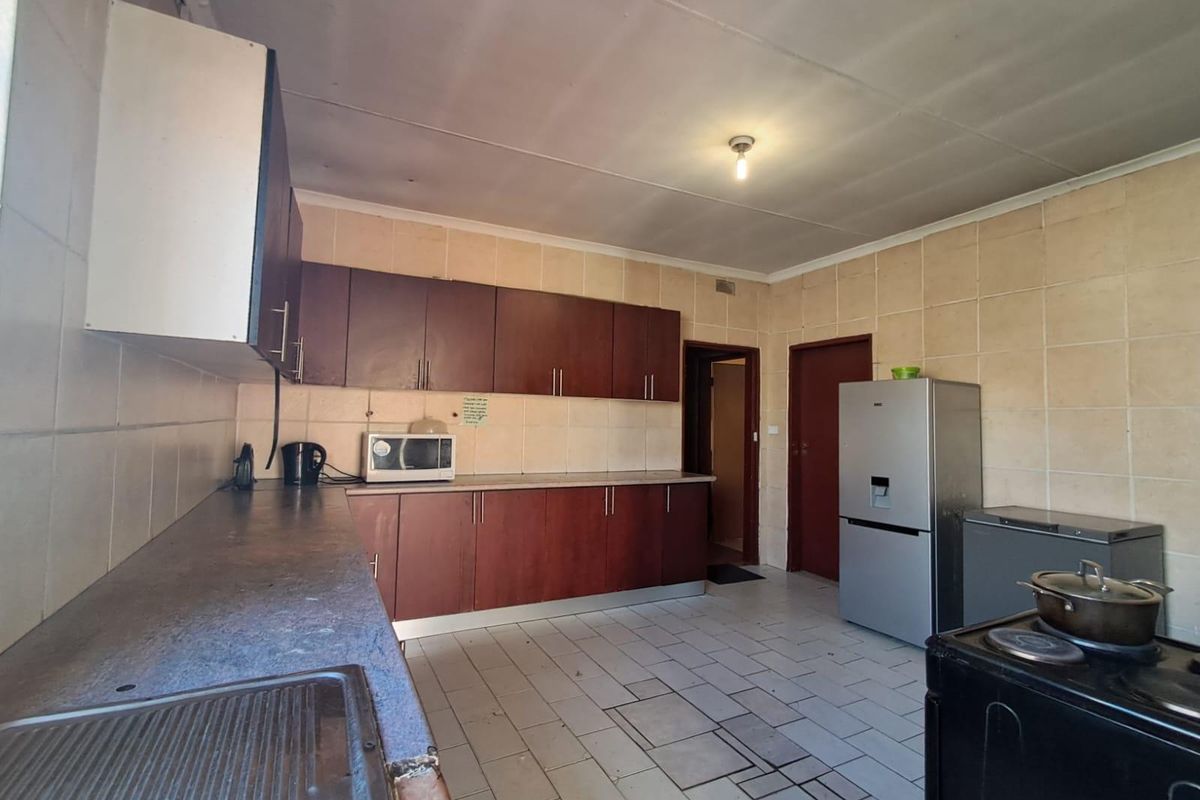 A functional kitchen featuring dark wood-finish cabinetry, tiled splashbacks, and tiled flooring, offering a dated aesthetic with potential for modern renovation.