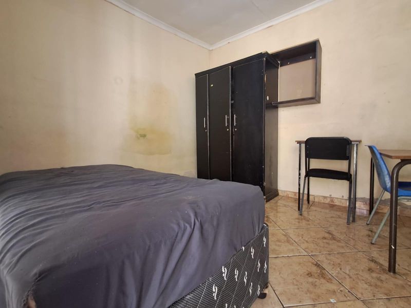 A bedroom featuring tiled flooring and coving, currently showing significant wall staining and wear, requiring cosmetic updates to improve the overall condition.