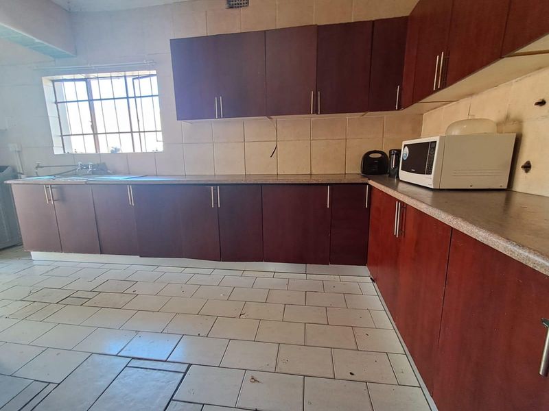A functional kitchen featuring dark wood-look cabinetry, tiled flooring, and a window with security bars, offering a blank canvas for potential modern updates.