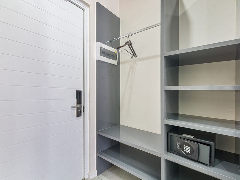 A functional bedroom storage area featuring a built-in wardrobe with shelving, a hanging rail, and a secure built-in safe.