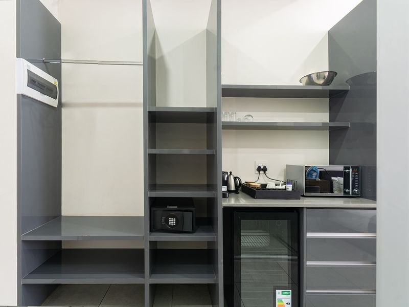 A functional utility space featuring modern grey built-in cabinetry, open shelving, a countertop, and an integrated electrical distribution board.