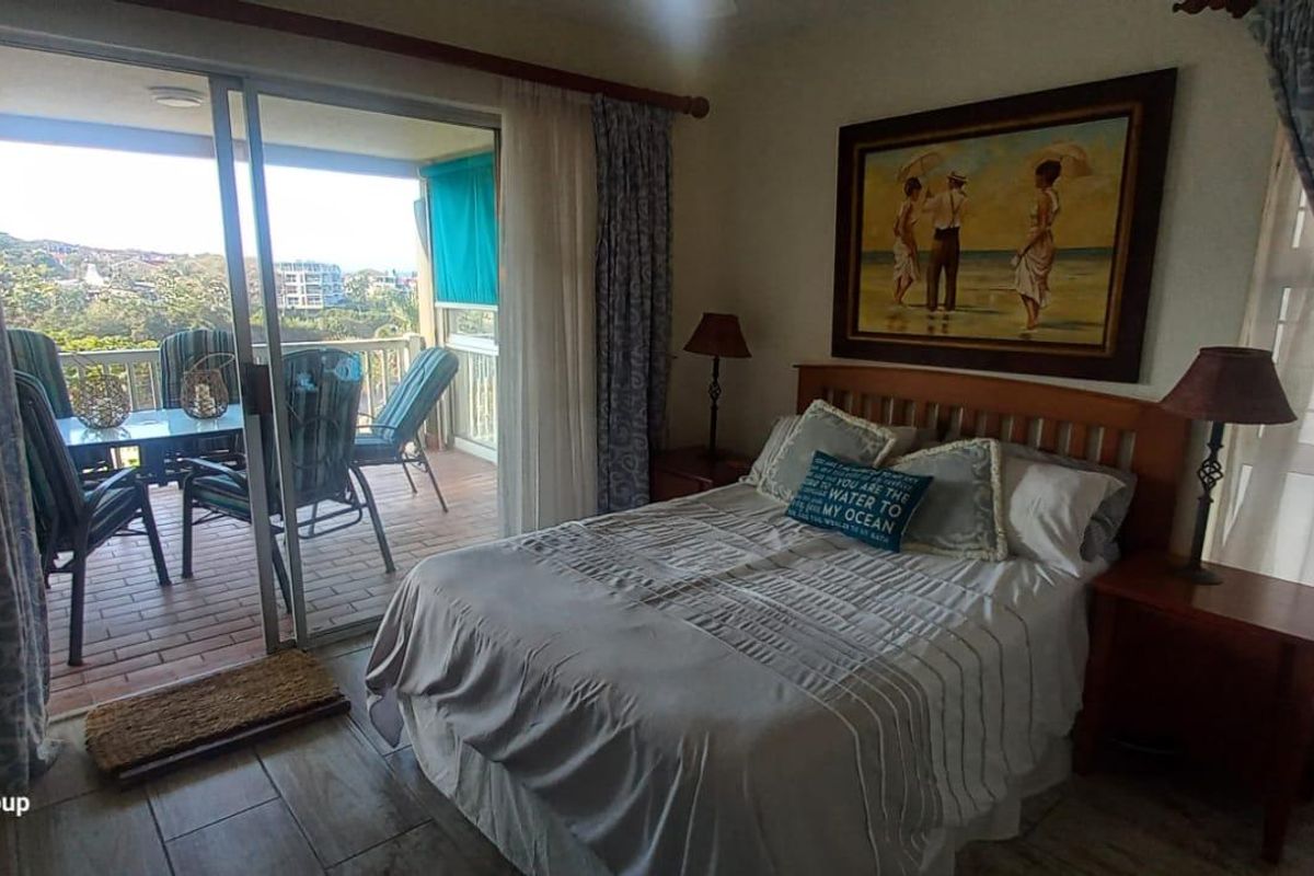 A comfortable bedroom featuring tiled flooring and a large sliding glass door that provides direct access to a private balcony with outdoor seating.