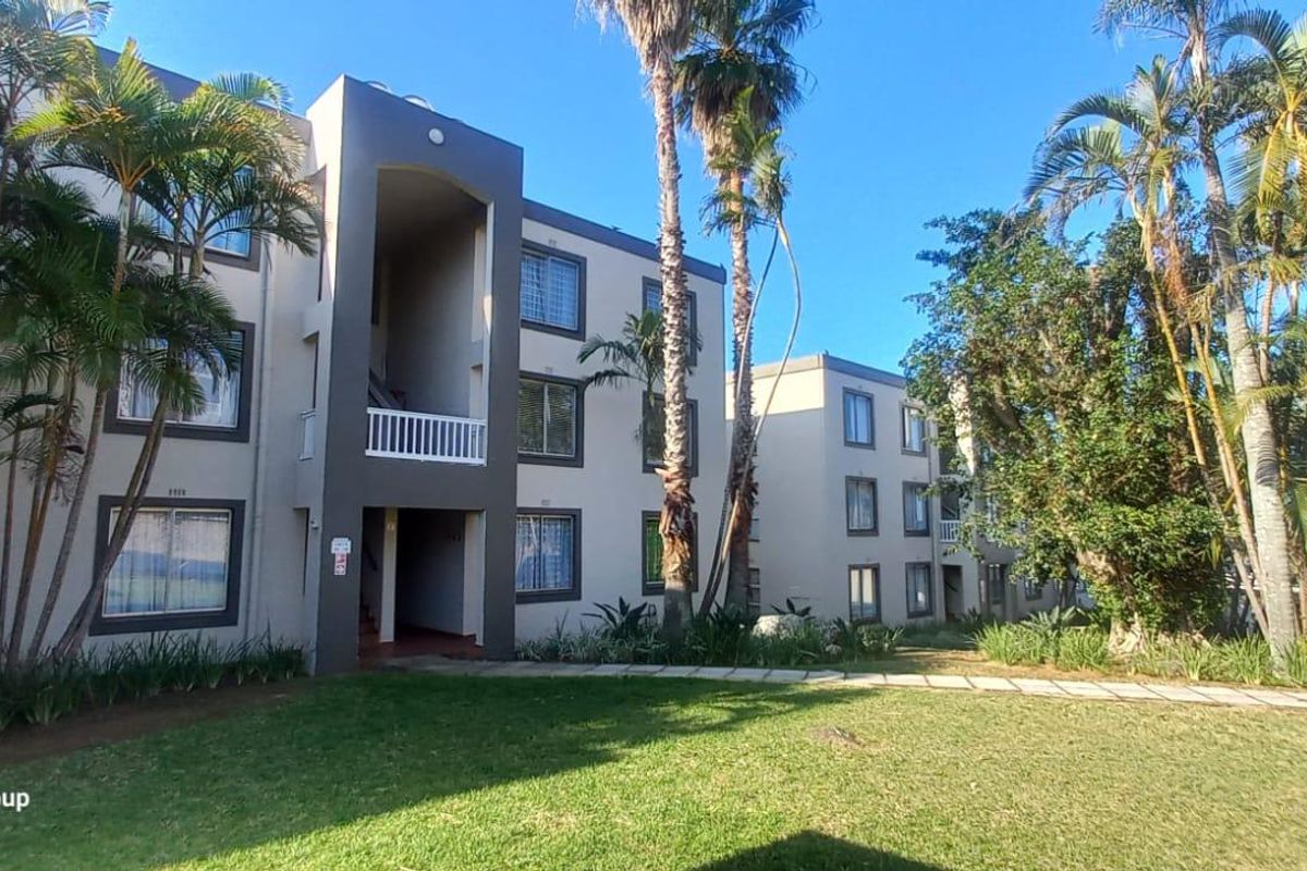 Exterior view of a multi-story apartment complex featuring landscaped gardens, paved walkways, and private balconies.