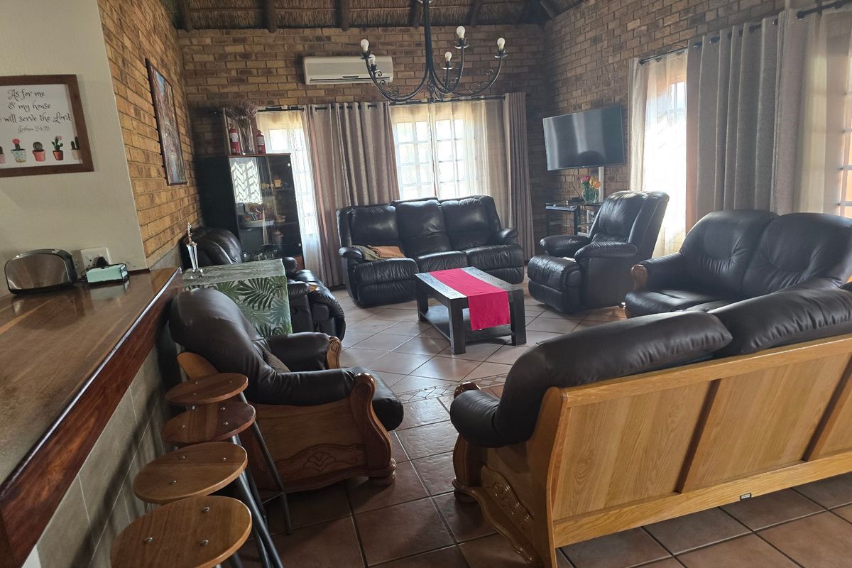Spacious living room featuring exposed brick walls, a high thatched ceiling, ceramic tiled flooring, and a breakfast bar area.