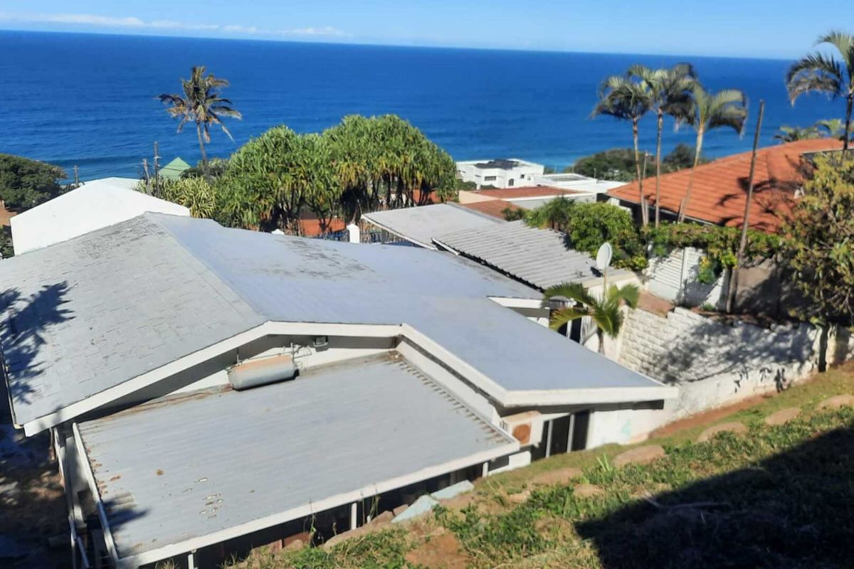 Aerial view of the property showing the roof structure and surrounding coastal landscape with ocean views.