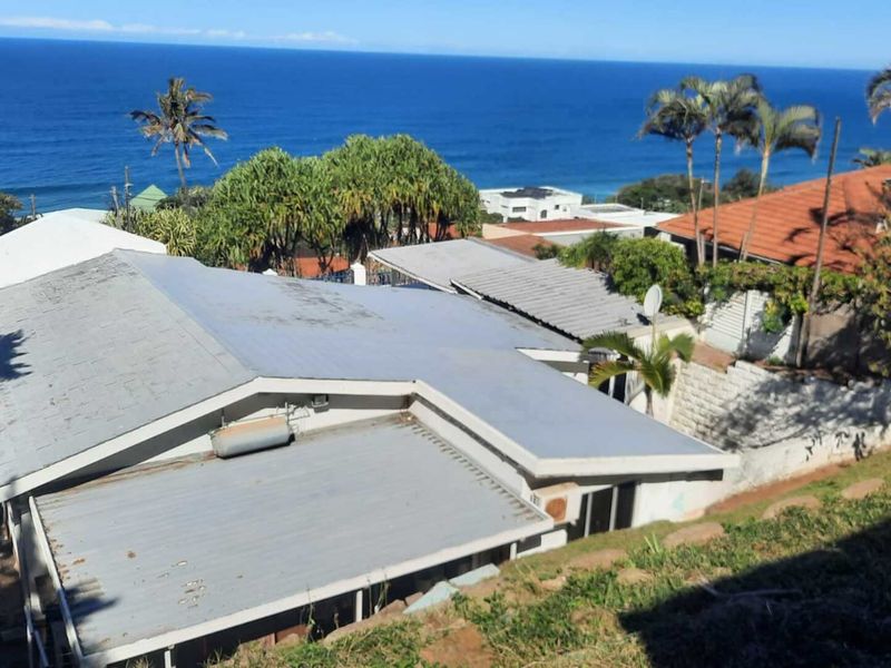 Aerial view of the property showing the roof structure and surrounding coastal landscape with ocean views.