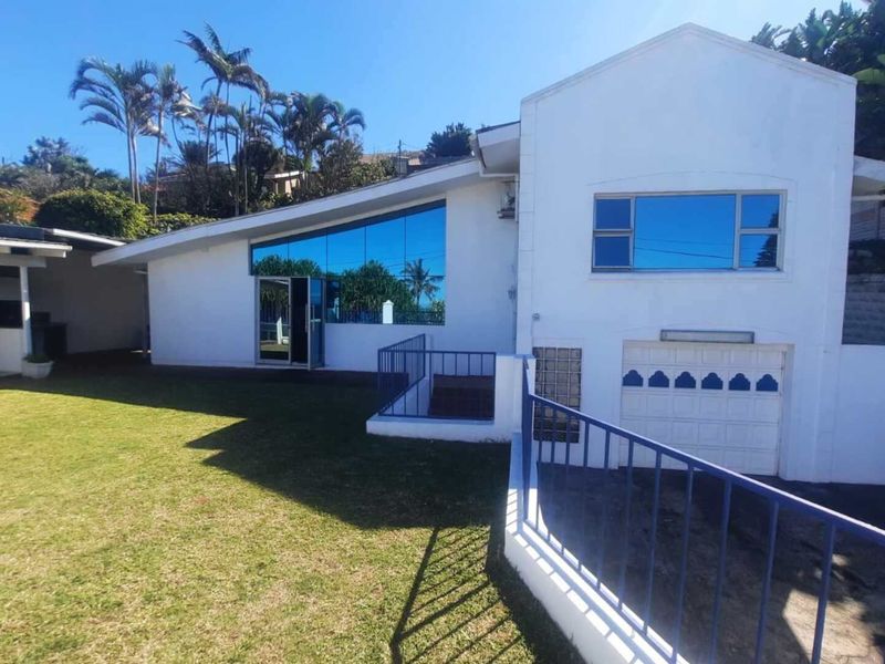 Rear view of the property featuring a lawn, covered patio area, and a single garage with reflective windows.