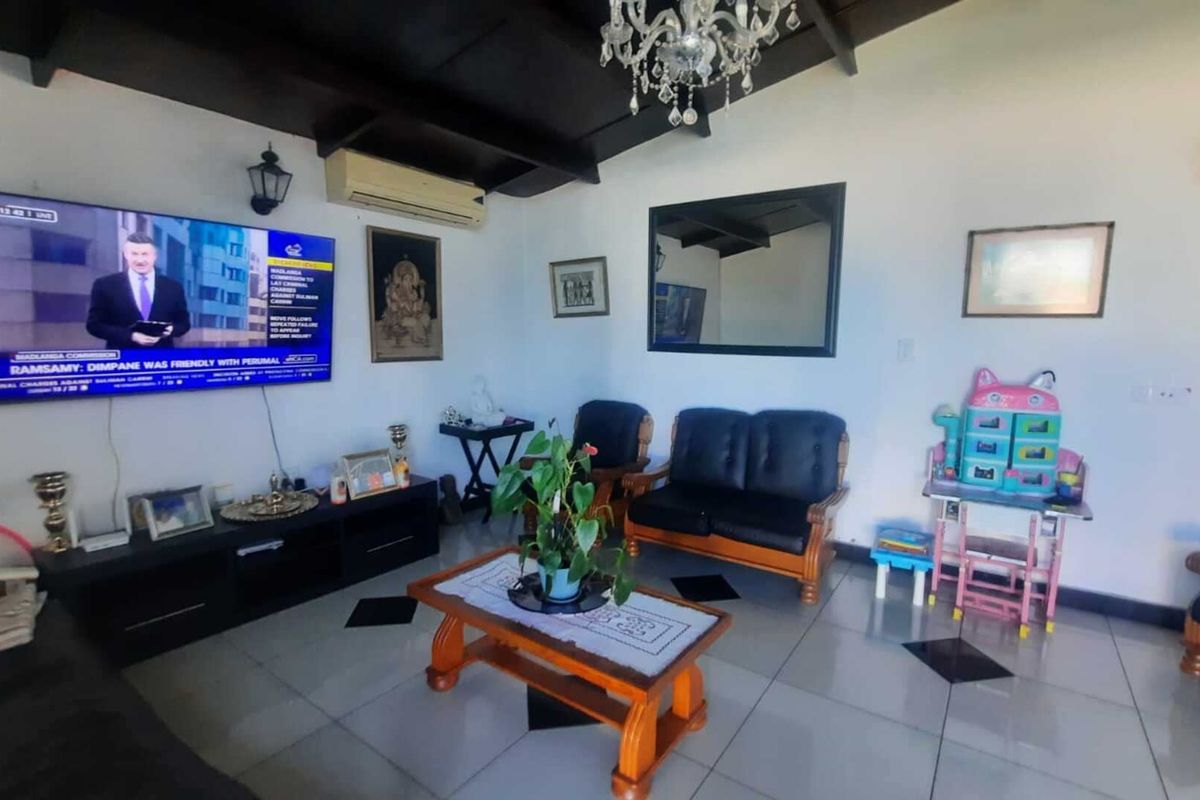 A living room featuring tiled flooring, exposed beam ceilings, and wall-mounted lighting, providing a functional space for relaxation.