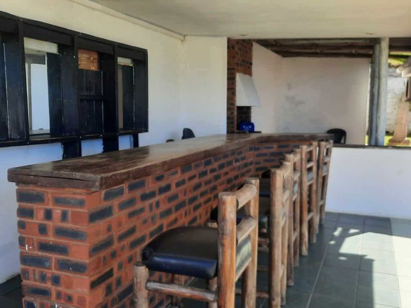 Outdoor entertainment area featuring a built-in brick bar counter and fireplace, perfect for hosting guests in a covered patio setting.