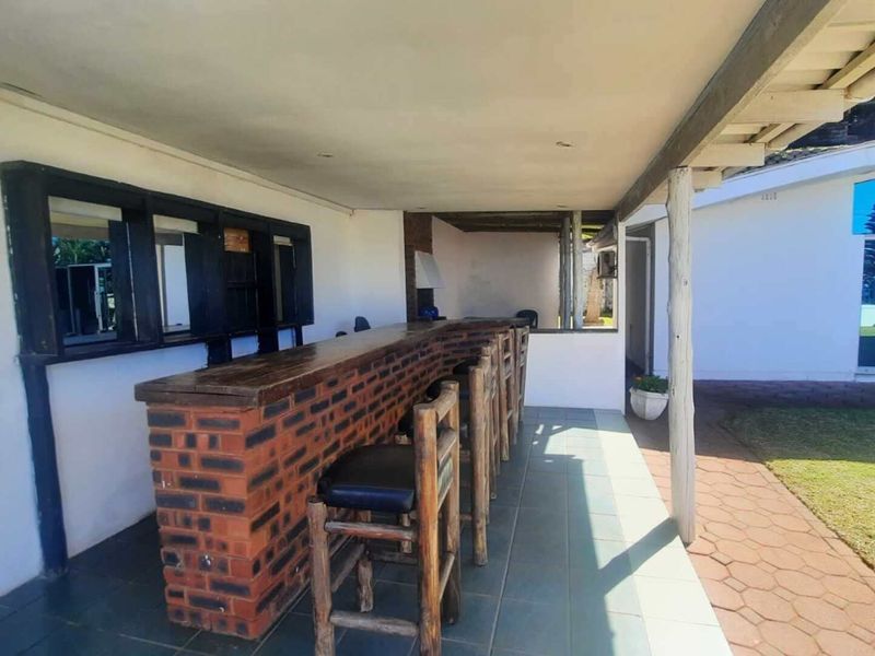 Covered outdoor patio featuring a built-in brick bar counter, tiled flooring, and timber support posts, ideal for outdoor entertaining.