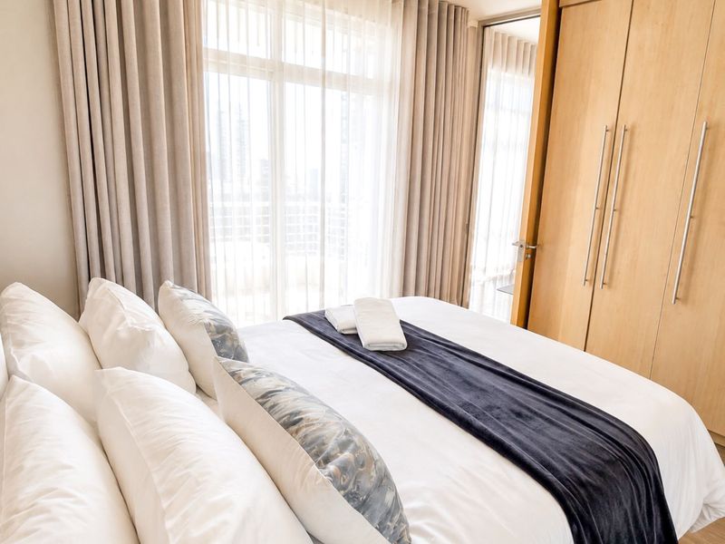 A well-maintained bedroom featuring built-in cupboards and large sliding glass doors that provide ample natural light.