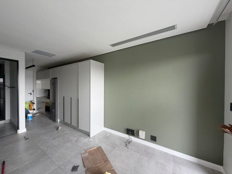 Modern open-plan living area featuring sleek built-in cabinetry, neutral tiled flooring, and integrated ducted air conditioning in a contemporary apartment setting.