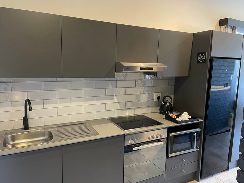 Modern kitchen featuring sleek grey cabinetry, subway tile backsplash, integrated appliances, and a contemporary black mixer tap.