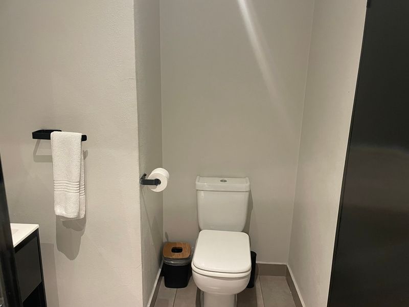 A clean and modern bathroom featuring a white toilet, tiled flooring, and matte black fixtures.