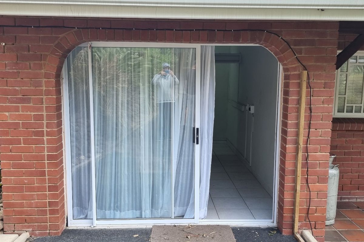 A view of a brick exterior featuring an arched entrance with a sliding glass door leading into a tiled interior space.