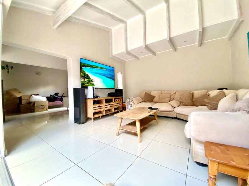 Spacious living room featuring large format floor tiles and distinctive exposed ceiling beams, creating an open and airy atmosphere.