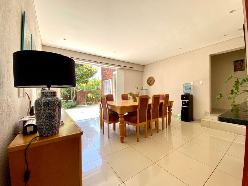Spacious dining area featuring polished porcelain floor tiles, recessed lighting, and large sliding glass doors providing direct access to the rear garden.