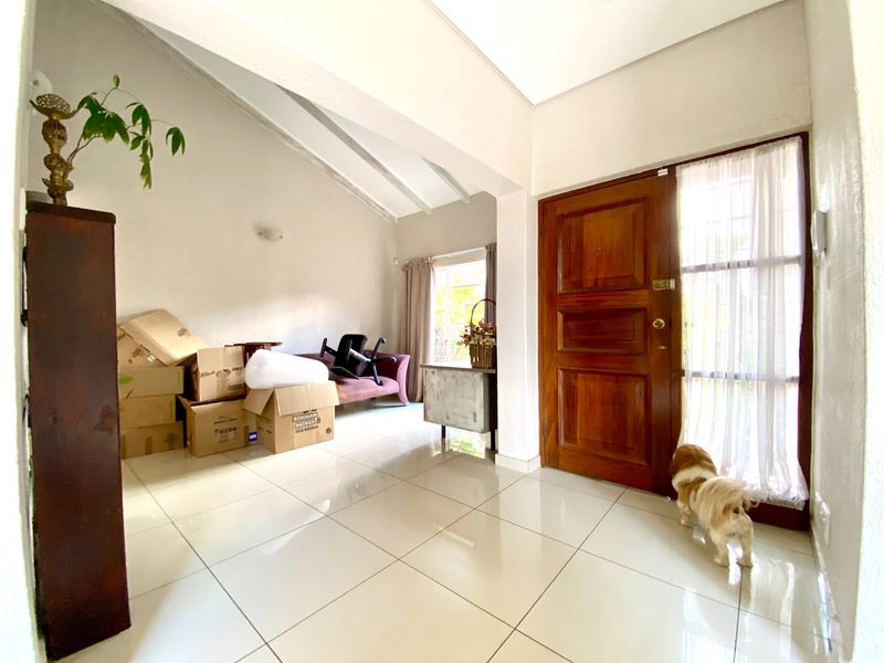 Entrance foyer featuring tiled flooring, exposed beam ceiling, and a solid timber front door with a side window panel.