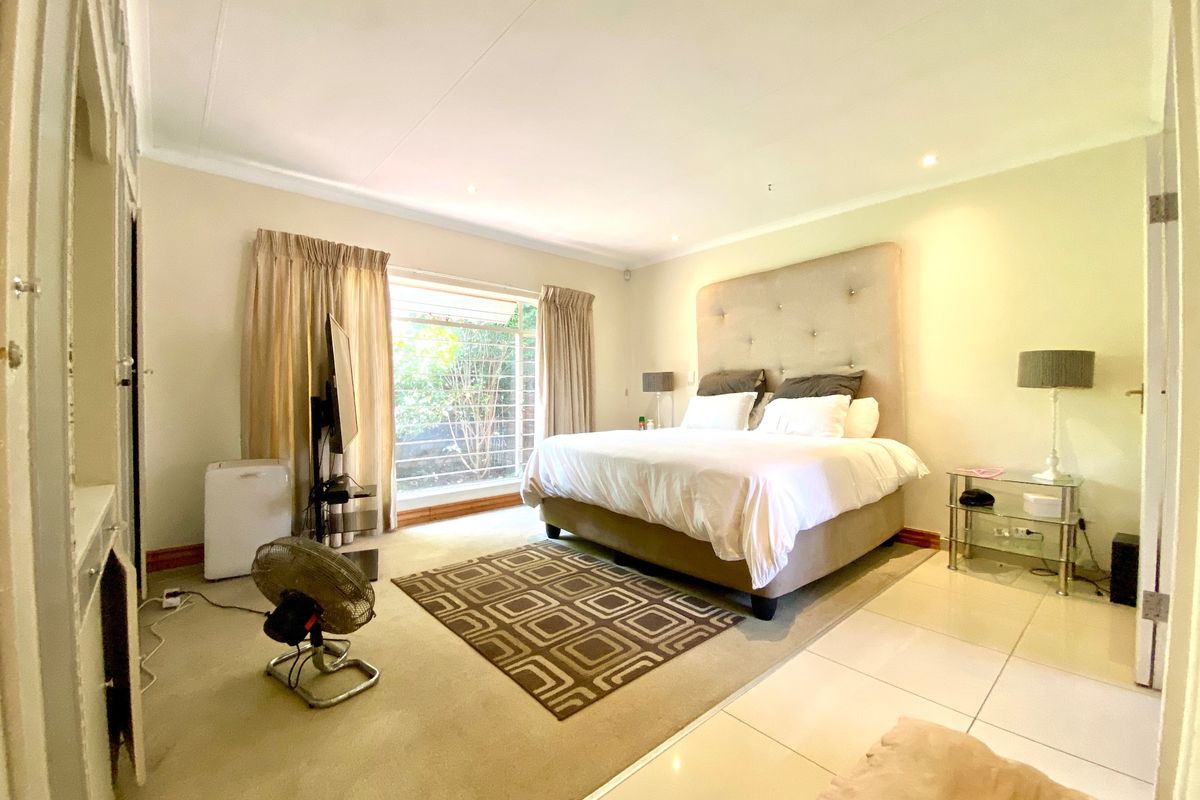 Spacious bedroom featuring a mix of tiled and carpeted flooring, recessed downlighting, and large windows with security bars.