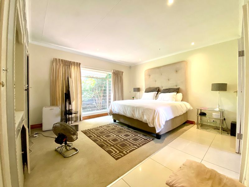 Spacious bedroom featuring a mix of tiled and carpeted flooring, recessed downlighting, and large windows with security bars.