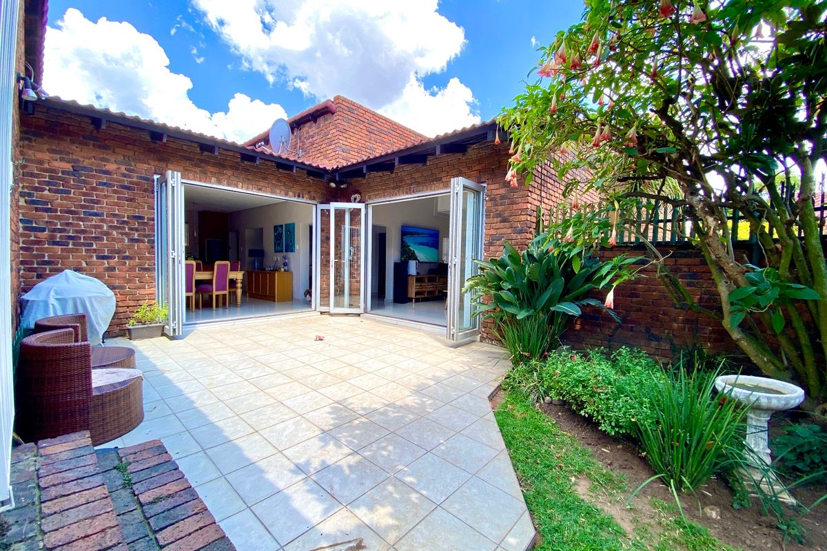 A well-maintained rear patio featuring tiled flooring and bi-fold doors that open into the living area, set against a face brick townhouse exterior.