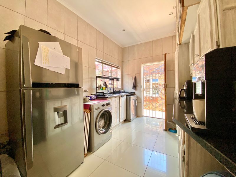 Functional laundry area featuring tiled walls and floors, built-in cabinetry with granite countertops, and direct access to the exterior via a security gate.