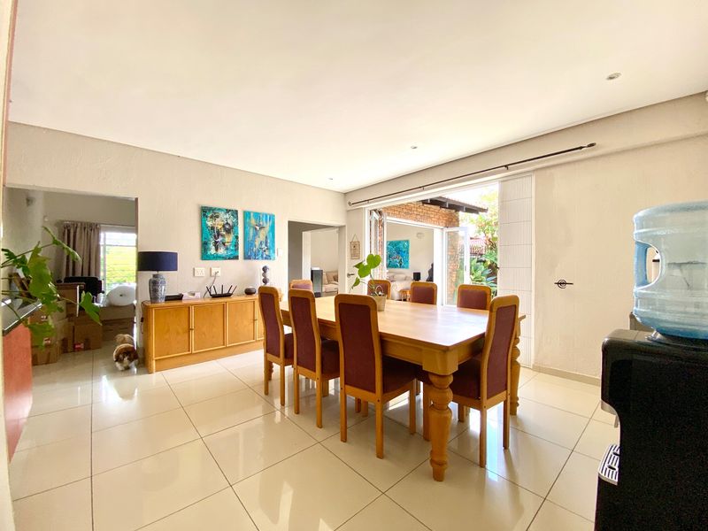 Spacious open-plan dining area featuring large format floor tiles, recessed lighting, and seamless access to the outdoor patio through sliding glass doors.