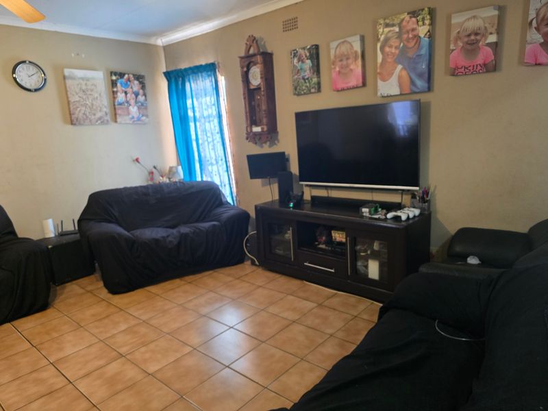 A living room featuring ceramic floor tiles and a ceiling fan, providing a functional space for relaxation.