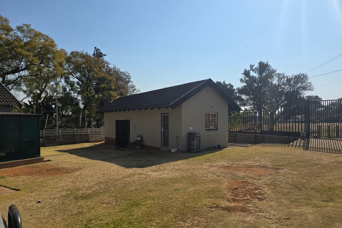 A view of the rear exterior of the property featuring a detached structure with a tiled roof and surrounding garden area.
