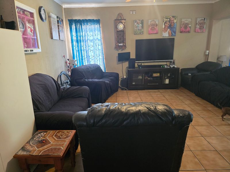 A spacious living room featuring ceramic tile flooring and a ceiling fan, providing a functional and comfortable family living area.