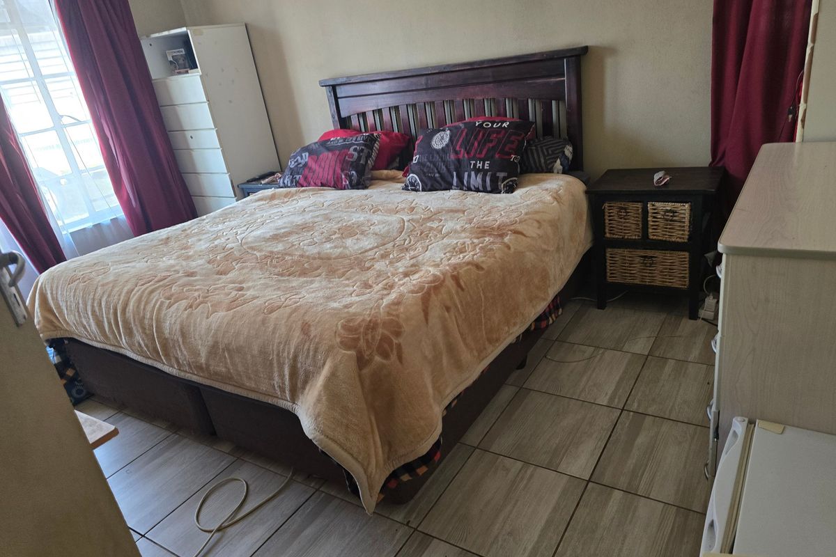 A functional bedroom featuring tiled flooring and a window, providing a neutral base for potential interior updates.