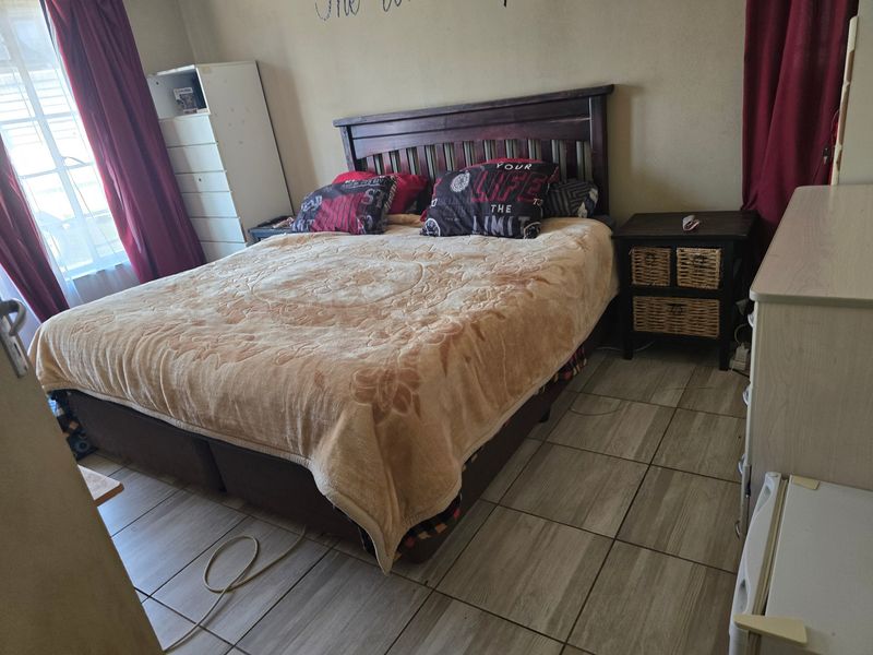 A functional bedroom featuring tiled flooring and a window, providing a neutral base for potential interior updates.
