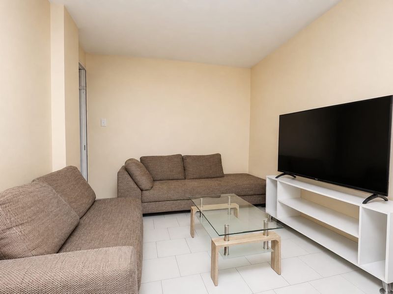 A simple living room featuring neutral wall tones and light-colored tiled flooring, providing a functional and clean space.