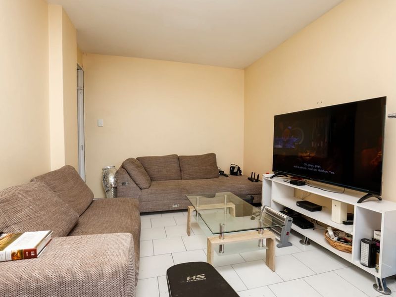 A living room featuring neutral wall paint and tiled flooring, providing a functional and versatile space for relaxation.