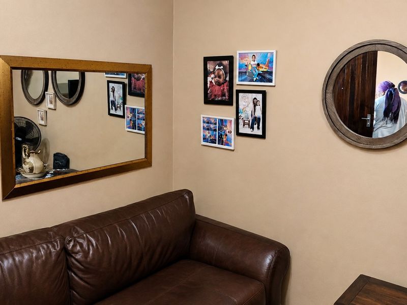 A corner view of a living room featuring neutral wall paint and multiple decorative wall mirrors.