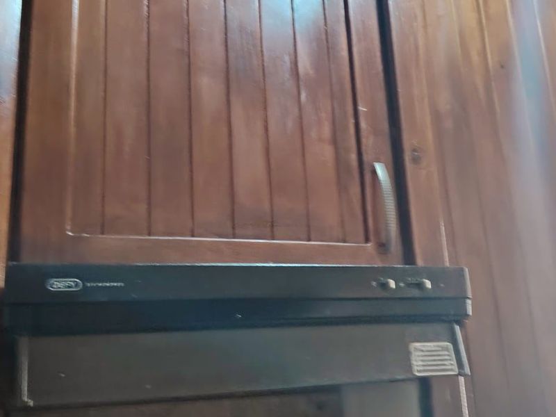 Close-up view of traditional wooden kitchen cabinetry featuring a built-in extractor fan unit.